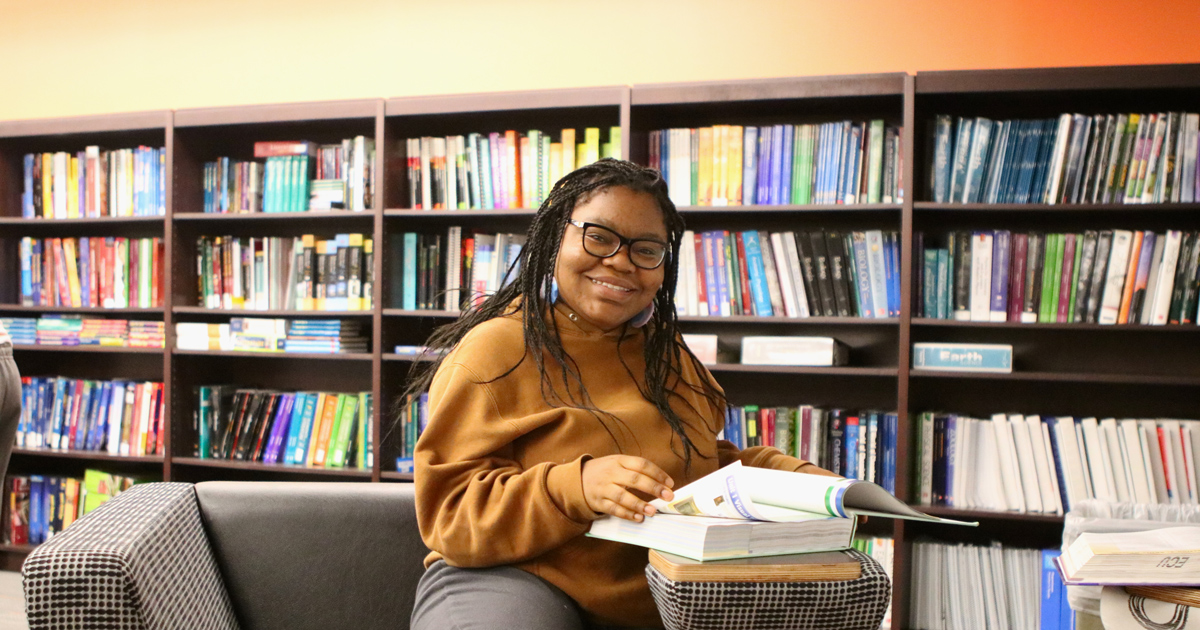 Education student sitting in library reading a book