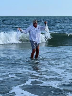 Dr. Choate standing in waves holding a net with small fish in it