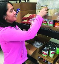 Student stocks shelves at ECU food pantry.