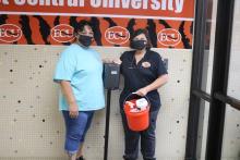 ECU cleaning crew stands next to hand-sanitizing station.