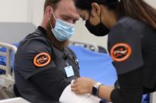 ECU Nursing student Gabriel Rebischke sits patiently while fellow student Suja Shresta practices applying bandages to his arm.