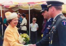 Queen Elizabeth II shakes an Army liaison’s hand while Dr. Steve Gardner, next to him, looks on.